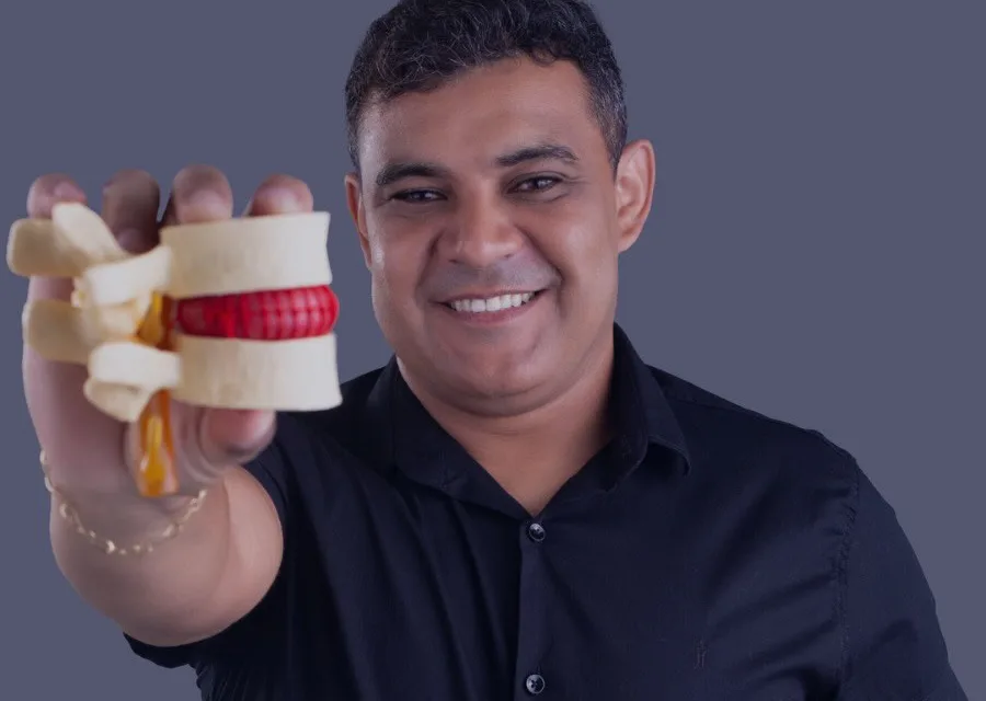 Dr. Bruno segurando um modelo de vértebra com hérnia de disco